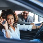 Una donna al volante mostra le chiavi della sua auto nuova.