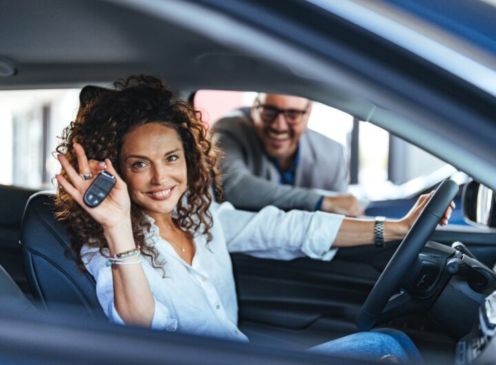 Una donna al volante mostra le chiavi della sua auto nuova.